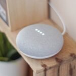 A Google Home Mini smart speaker on a wooden shelf, blending technology with home decor.